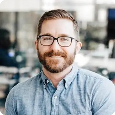 a smiling man with glasses and a beard