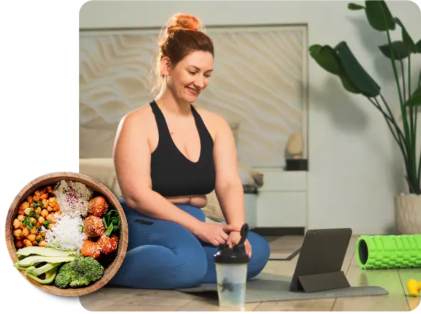 a woman sits on the floor with a laptop beside her and a bowl of food in her lap